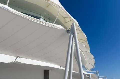 Low-angle view of modern white tensile canopy and steel support poles again.. Stock Photos