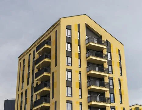 Low-angle view of a modern yellow apartment building facade featuring geome.. Stock Photos