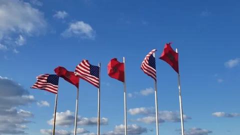 Low angle view of Moroccan and USA Flags waving against blue sky Stock Footage 154222725