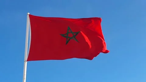 Low angle view of the Moroccan flag waving against blue sky Stock Footage 227352544