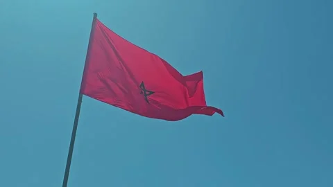 Low angle view of Moroccan Flag waving against blue sky - Kingdom of Morocco Fla Stock Footage 285639184