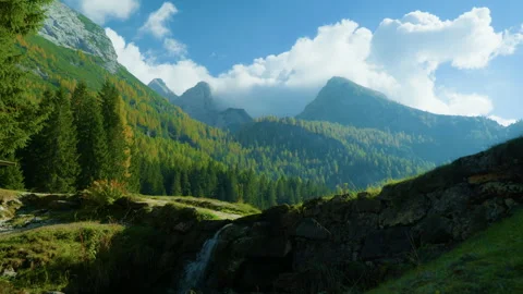Low Angle View of Mountain Valley and Forested Range with Waterfall Foreground Stock Footage 320174203
