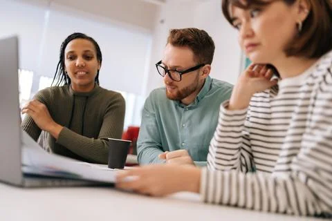 Low-angle view of multicultural business group talking at meeting table in Stock Photos