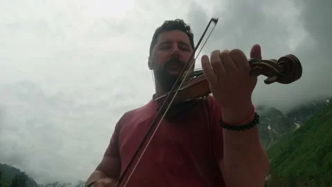 Low angle view of musician playing violin in mountains. Music everywhere Stock Footage 142287253