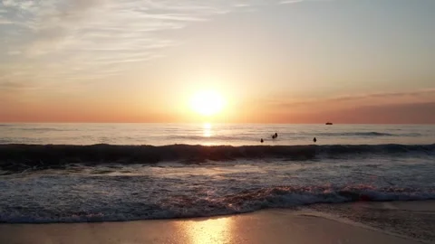 Low angle view to the ocean with calm waves during sunset with surfers on b.. Stock Footage 249625332
