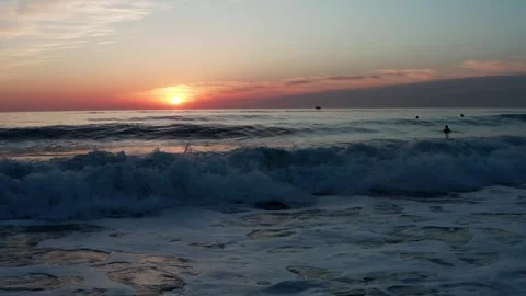 Low angle view to the ocean with small waves during sunset with surfers on .. Stock Footage 249625228