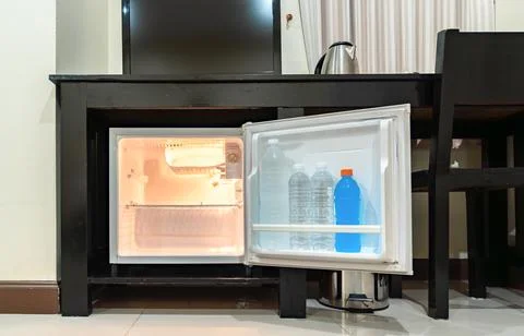 Low angle view of the opened mini fridge with water bottles placed under wo.. Fotos de archivo