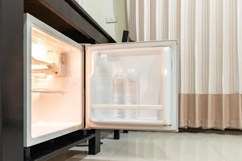 Low angle view of the opened mini fridge with water bottles placed under wo.. Fotos de archivo