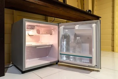 Low angle view of the opened mini fridge with water bottles placed under wo.. 스톡 사진