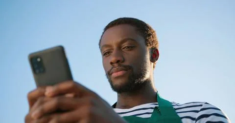 Low angle view of the optimistic multiracial farmer scientist in apron using Stock Photos