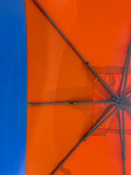 Low angle view of orange beach or poolside umbrella against a blue sky, holiday Stock Photos