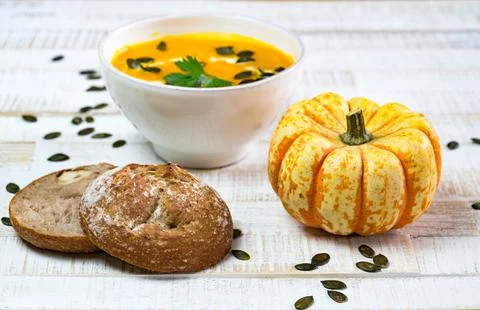 Low angle view of organic pumpkin soup in a white bowl framed by pumpkin and Stock Photos