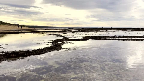 Low angle view over abstract low tide rock pools on Witsand shoreline Stock Footage 336203191