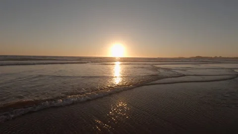 Low angle view over sandy beach at sunset, as waves rush towards camera Stock Footage 135422813
