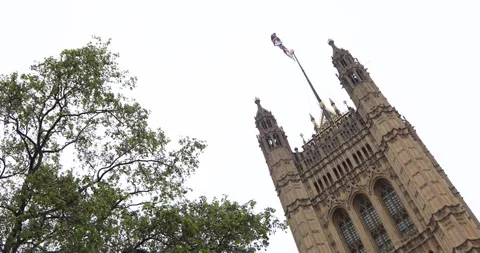 Low-angle view of Palace of Westminster tower, Union Jack whipping in the wind Stock Footage 319792700