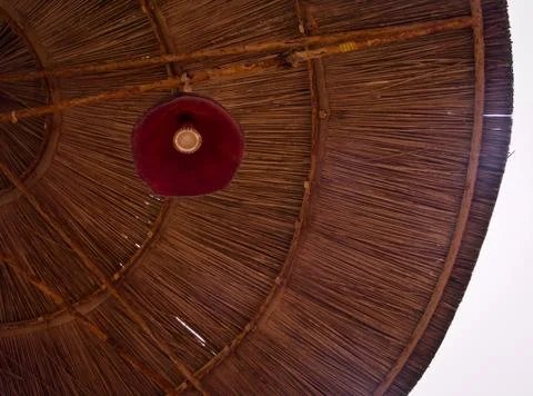 Low angle view of a parasol with red lamp in straw wicker pattern of lines Foto stock