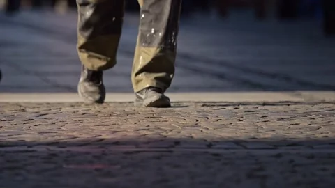 Low-angle view of pedestrians' winter shoes moving across a sunlit sidewalk.. Stock Footage 301954514