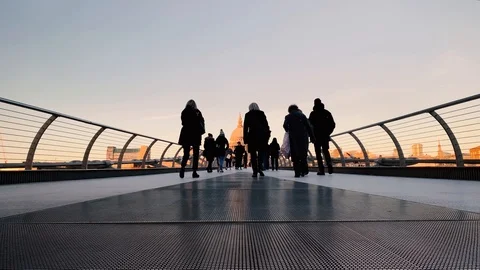 Low angle view of people walking on Millennium Bridge in London at sunset Stock Footage 99981116