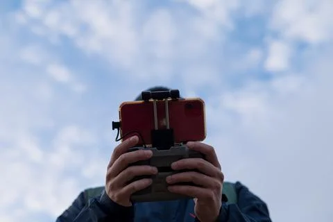 Low angle view of person using drone remote control Photos