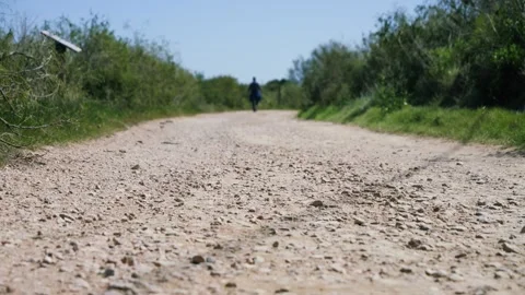 Low angle view of a person walking away along a gravel road in a rural area Video stock 335750854