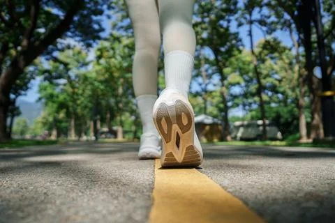 Low angle view of person walking on park road for active fitness lifestyle Stock Photos