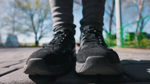 Low Angle View of Person Wearing Black Athletic Shoes Standing on a Brick Path Video stock 333824715