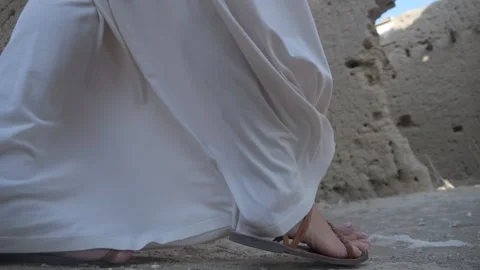 Low angle view of a person in a white robe and sandals walking near Vídeos de archivo 259407248