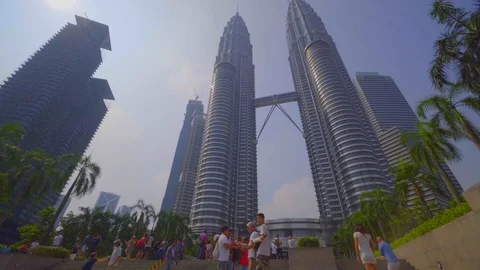 Low angle view of PETRONAS Towers against blue sky with tourist Stock Footage 122449721