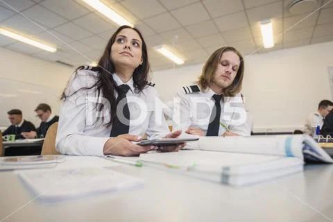 Low angle view of pilot trainees studying at desk in classroom Stock Photos