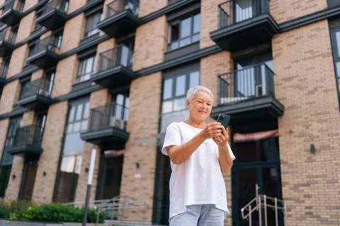 Low-angle view of positive senior attractive woman with gray hair standing on Stock Photos