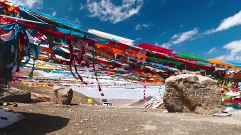Low angle view of prayer flags and rocks beneath a blue sky in Tibet Video stock 345883053