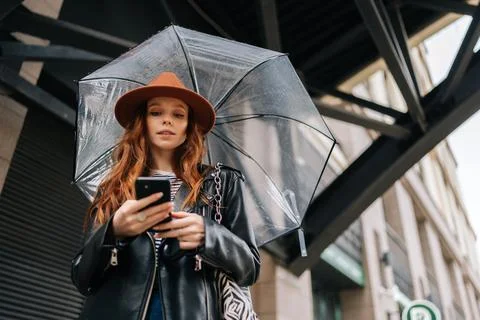 Low-angle view of pretty redhead young woman wearing fashion hat using typing Stock Photos