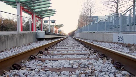 Low-Angle View of Railroad Tracks Leading to a Quiet Urban Train Station Stock Footage 301490364