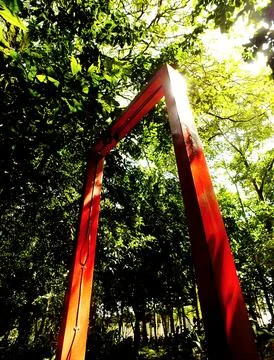 Low angle view. Red archway in a forest with sunlight shining through it. Foto stock