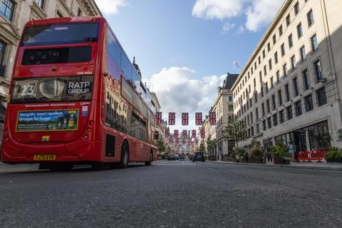 Low angle view of a red bus on a London street with flags. London, UK, 23 July 스톡 사진