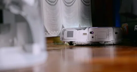 Low-angle view of a robot vacuum gliding across a wooden floor, LED sensor Video stock 328534069