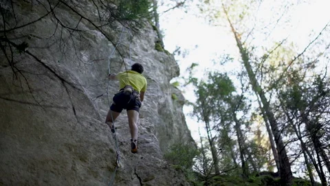 Low angle view of rock climber gripping safety rock during climb on cliff Video stock 131839120