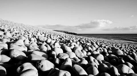 Low angle view of round stones on a beach in black and white Stock Photos