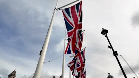 Low angle view of a row of union jack flags waving proudly in the wind, Vidéo 280108123