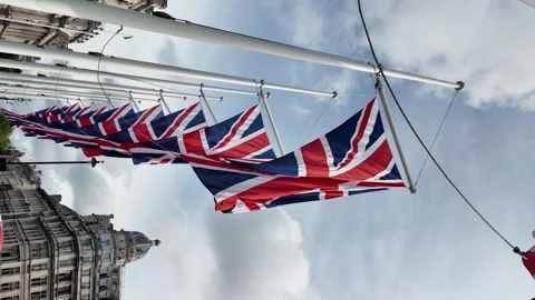 Low angle view of a row of union jack flags waving proudly in the wind, Vidéo 280135198