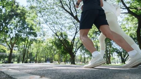 Low angle view of runners feet jogging on asphalt park path Photos