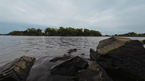 Low-Angle View of Sacramento River with Levee Riprap on a Cloudy Autumn Day Stock Footage 319960638