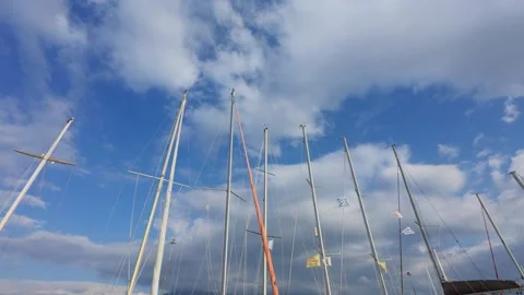 Low angle view of sailboat masts and flags against blue sky in marina Stock Footage 337459558
