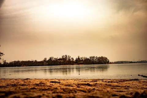 A low-angle view from a sandy shore looking out over a partially frozen lake  Stock Photos