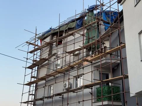 Low angle view of scaffolding around apartment facade and roof extension unde Stockfoto's