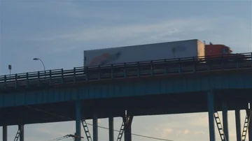 LOW ANGLE VIEW: Semi trucks driving on the overpass transporting goods at sunset Stock Footage 85758907