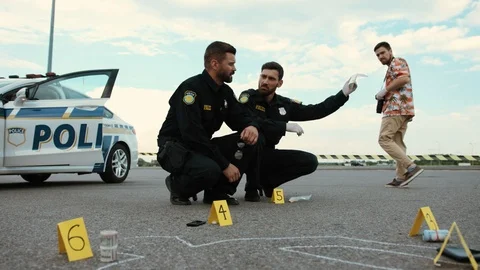 Low angle view of serious policemen at work examining drugs and body chalk Stock Footage 112982590