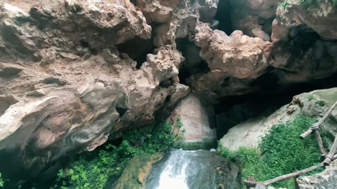 Low angle view shot of brown stone rock cave with small cascade falling into the Stock-Footage 317310787