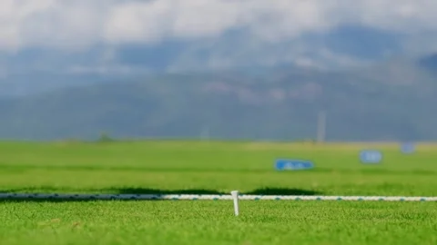 Low angle view shows a dark driver align with a tee mounted yellow ball, markers Vídeo Stock 329413256