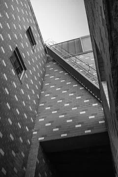 Low angle view of side street brick building with stairs - Black and white Stock Photos